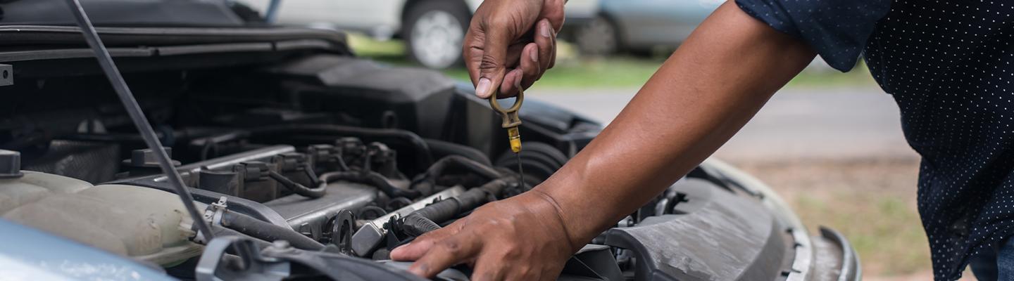 Auto Mechanic checking oil level pulling dip stick