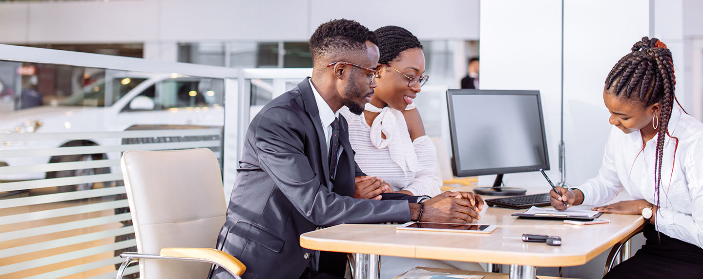 A man and woman purchasing a vehicle from a finance professional.