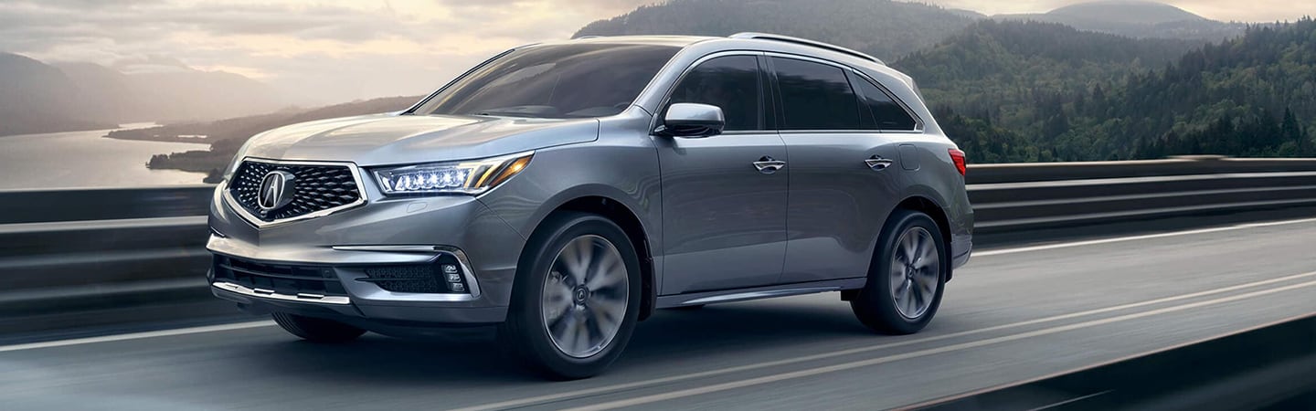 Silver MDX driving past water