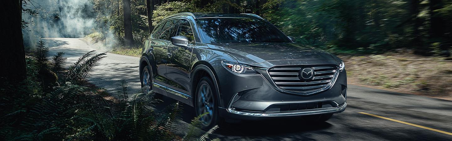 Front view of the 2020 Mazda CX-9 in motion driving through a forest