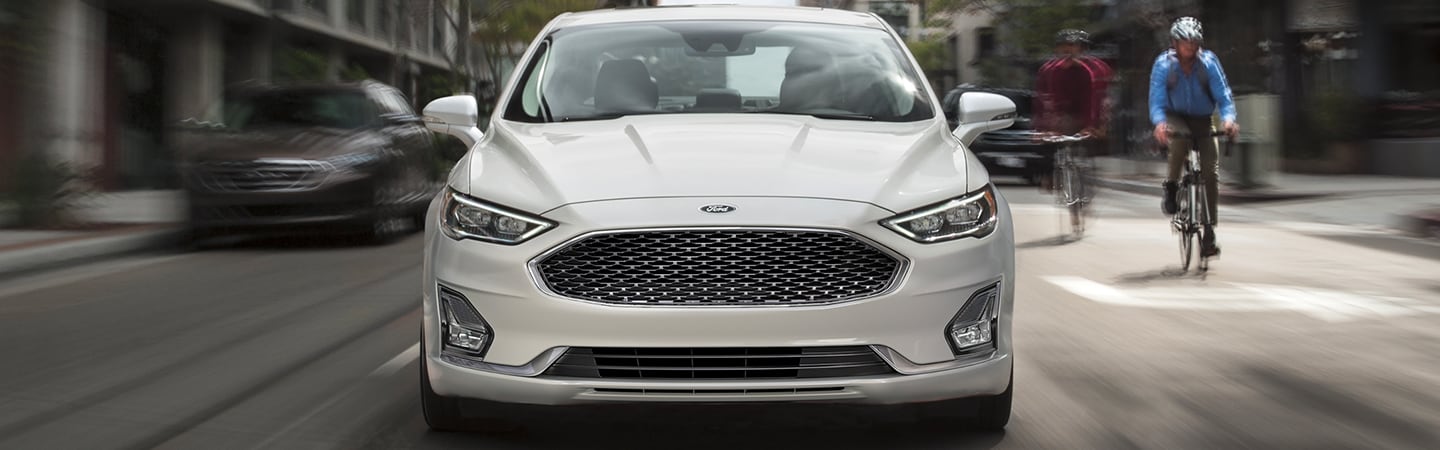 Front view of the 2020 Ford Fusion driving next to cyclists