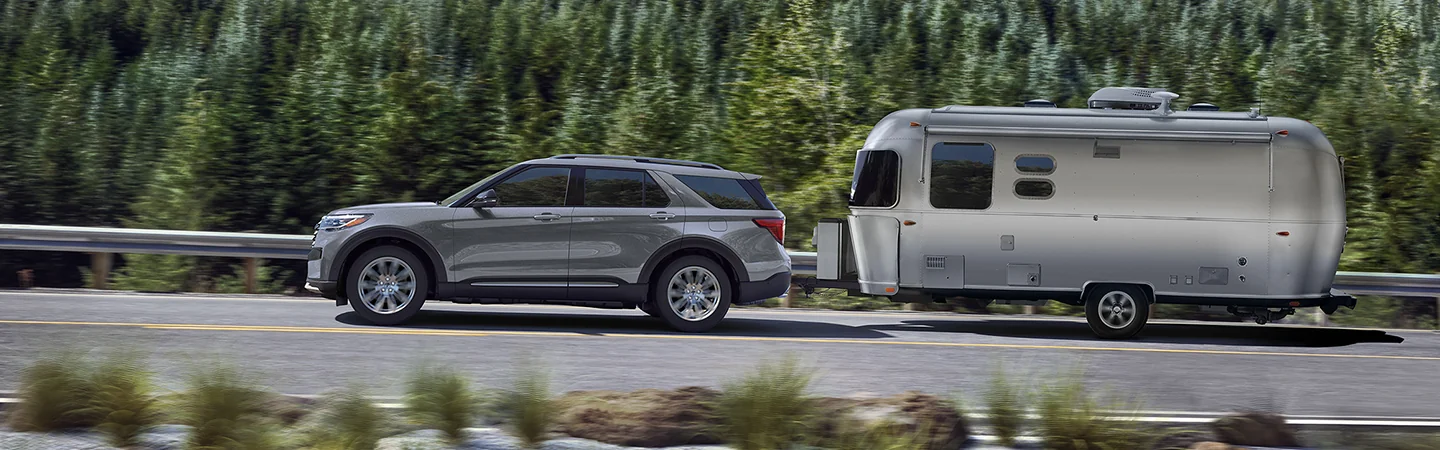 a silver 2026 Ford Explorer ST towing a camper