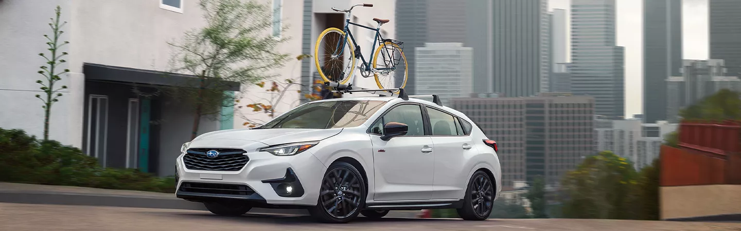 2026 Subaru Impreza with a bike rack on top, driving through a city