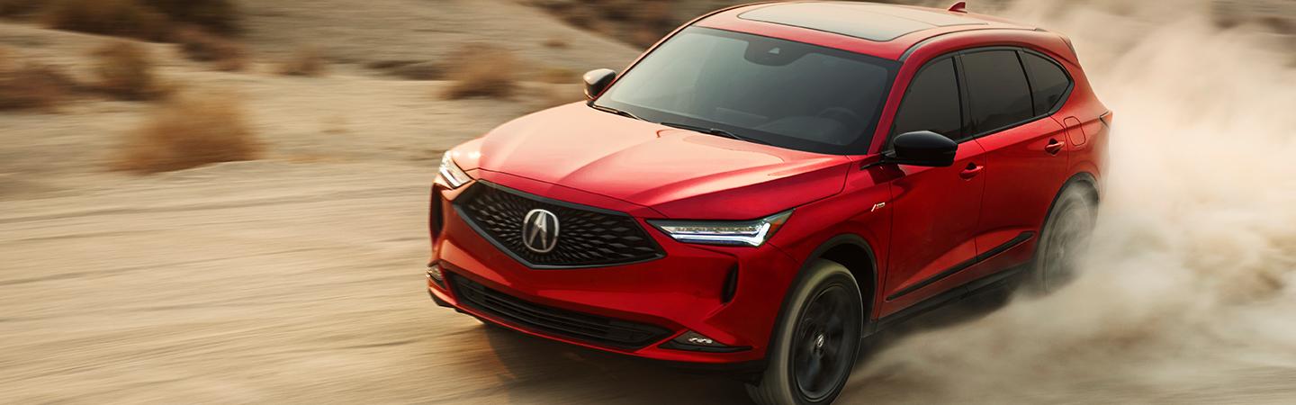 A 2022 Acura MDX in motion through a dirt road