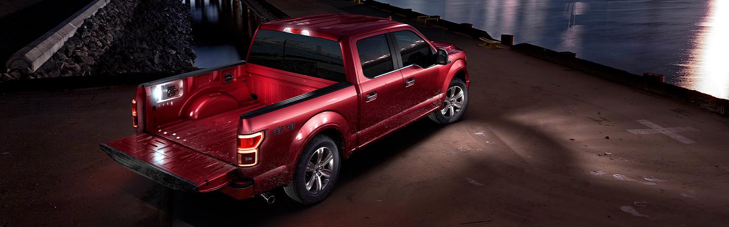 A red Ford F-150 tailgate down at night