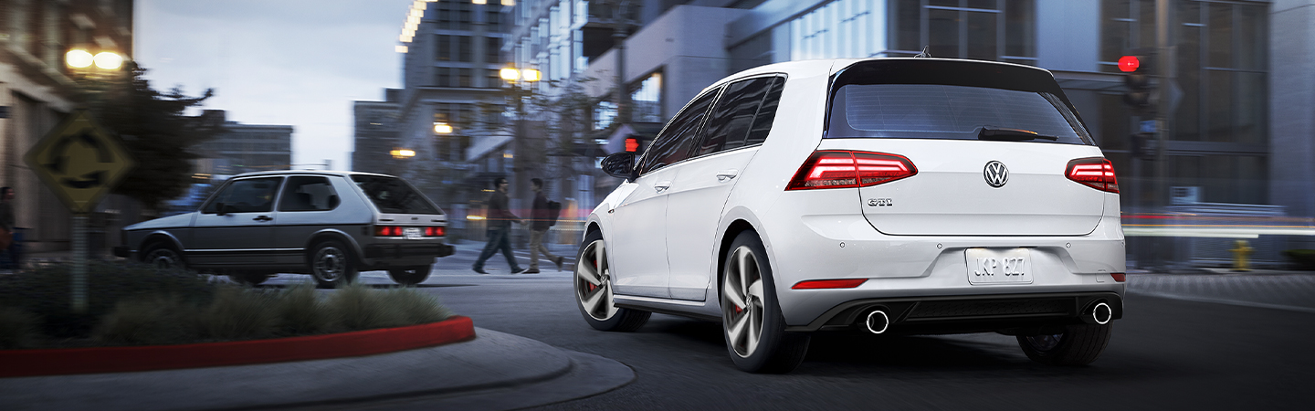 Rear view of a white 2020 Volkswagen Golf GTI driving through the city