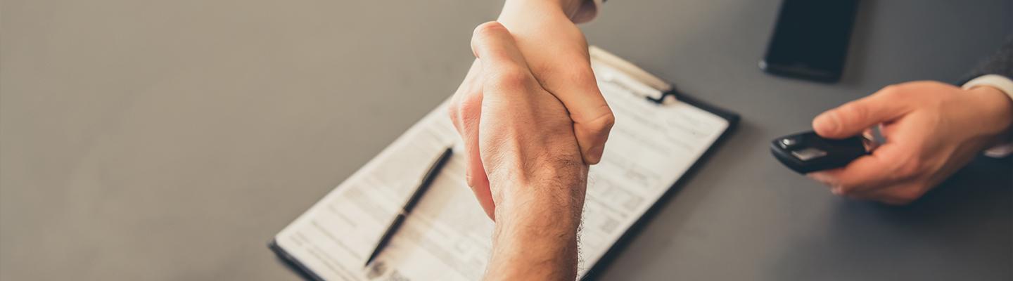 Closeup view of a customer and dealership employee shaking hands