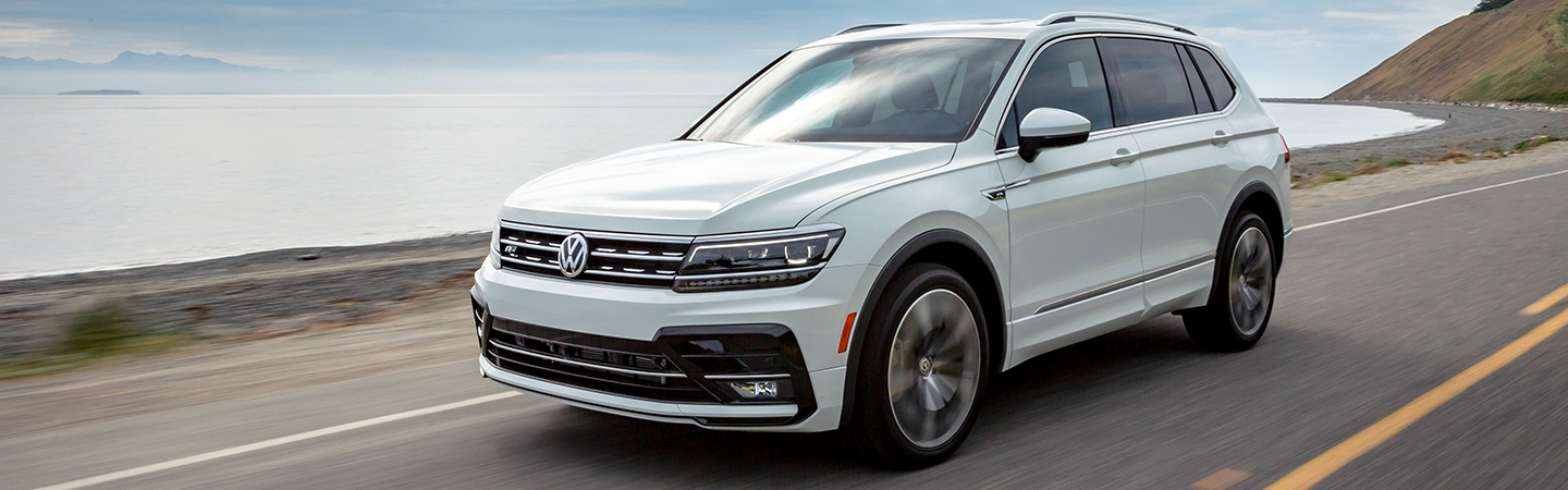 White Volkswagen Tiguan driving next to a lake