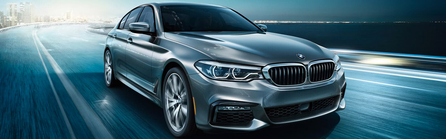 Gray BMW 5 Series front view, driving on a highway