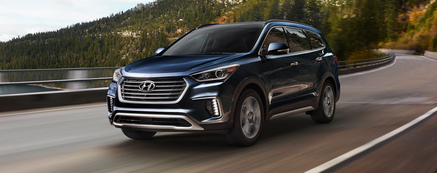 2019 Santa Fe XL front driver side view in motion driving on a mountain road.