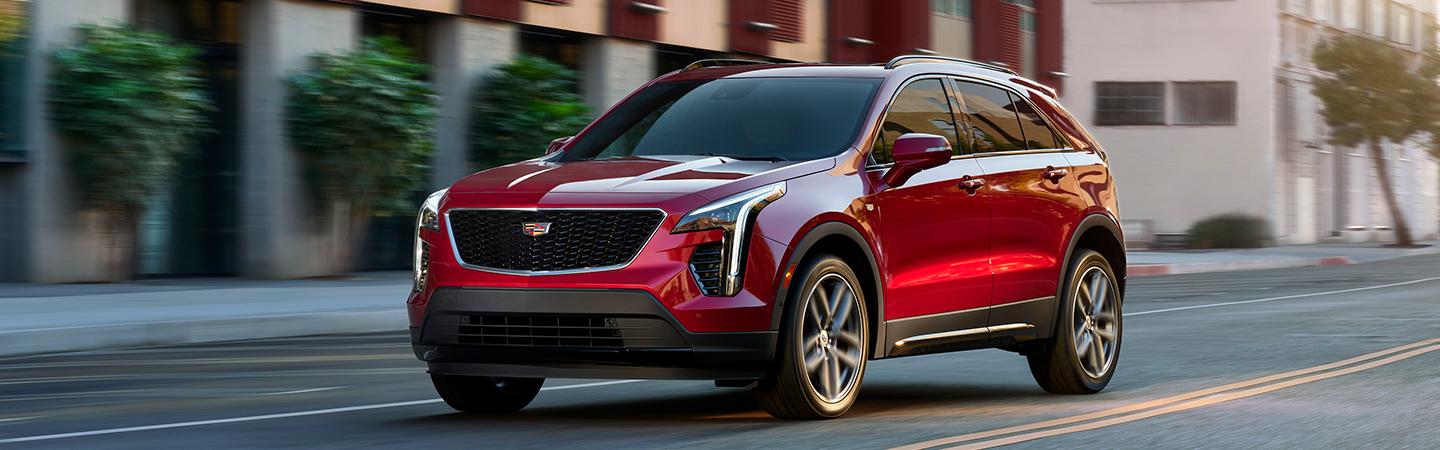 Red 2021 Cadillac SUV driving in coty