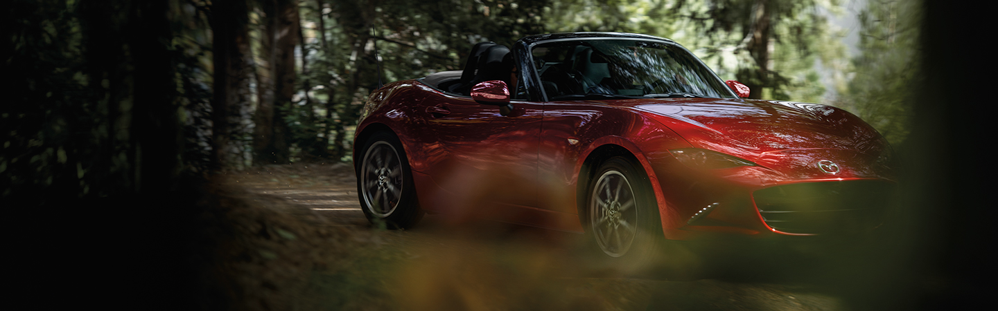 Front side view of a 2020 Mazda MX-5 Miata RF parked in the woods