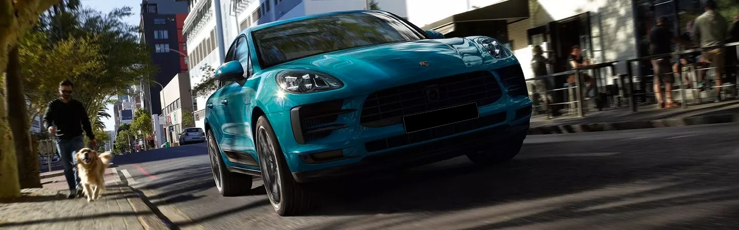 Blue Porsche Macan in motion on a city road