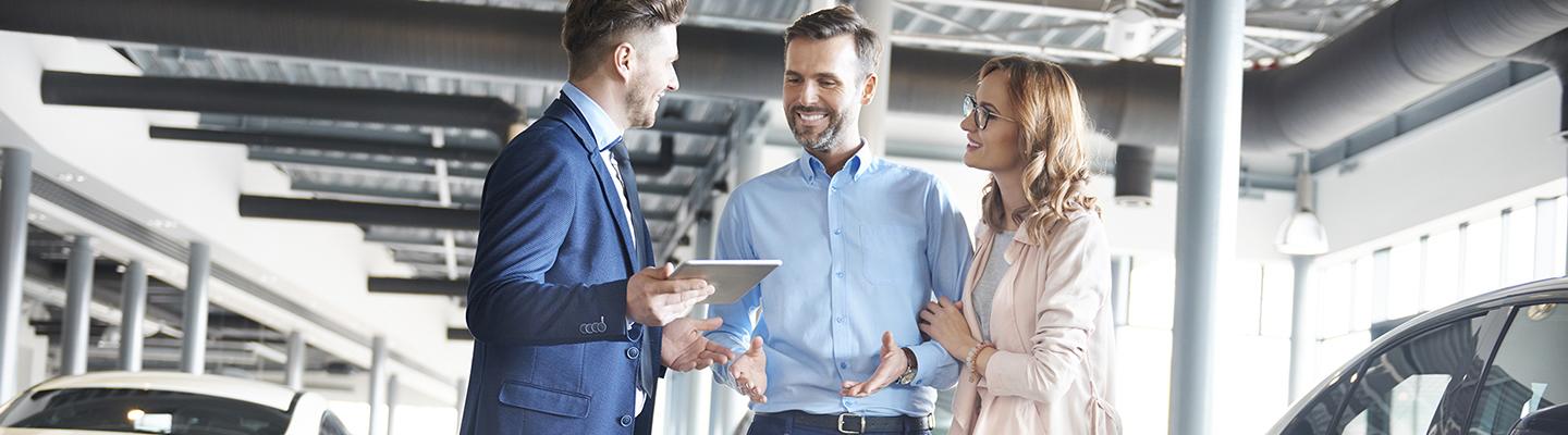 Woman and Man talking with salesman in dealship