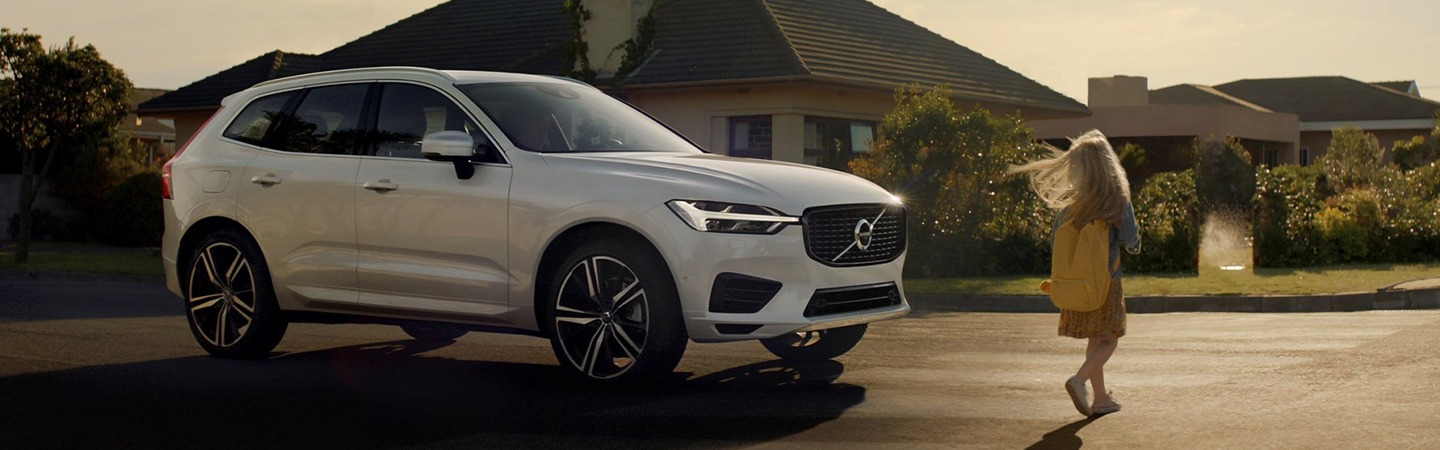 White 2021 Volvo XC60 parked next to a girl walking