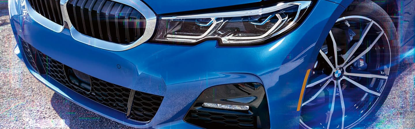 Close up of blue BMW 3 Series grill and wheel
