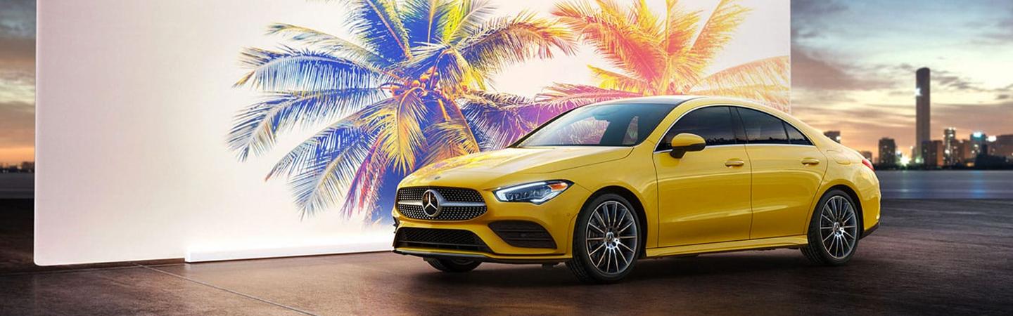 Yellow CLA parked in front of a palm tree picture