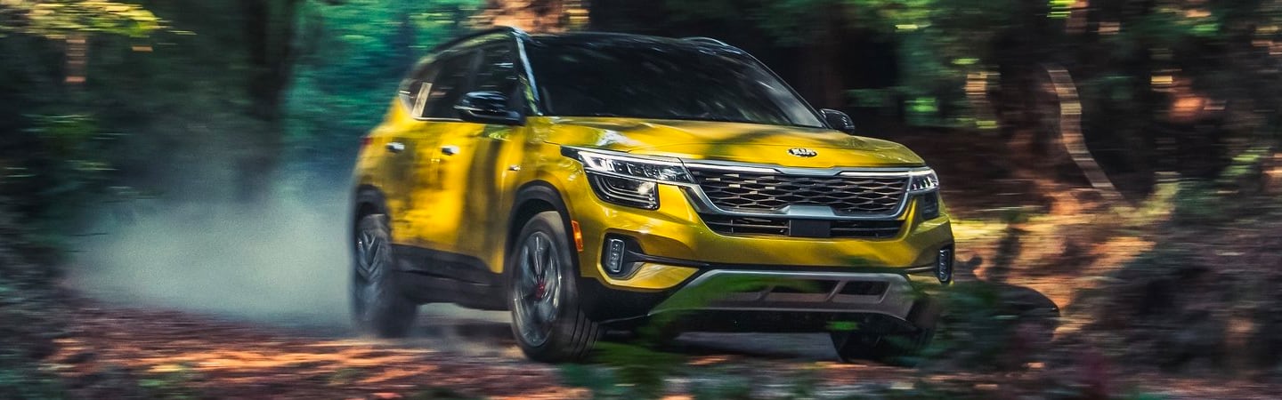 Yellow Kia Seltos in a forest trail