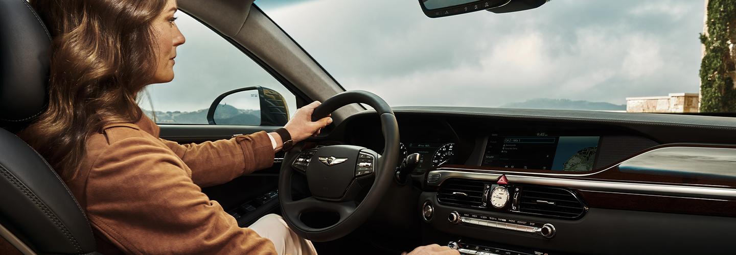 Woman holding the steering wheel inside of a Genesis G90
