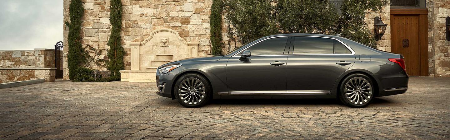 Driver’s side profile of gray G90 parked in front of a house