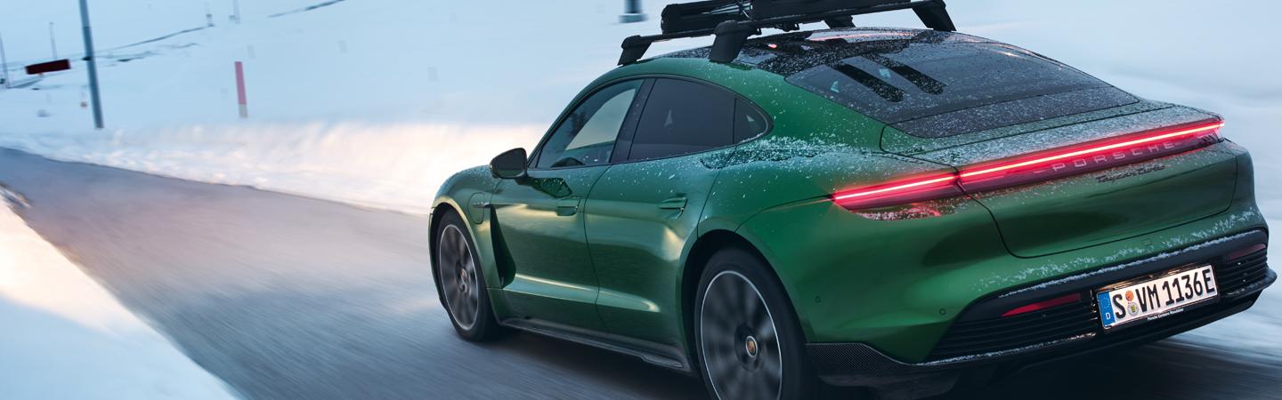 Green 2021 Porsche Taycan driving in the snow