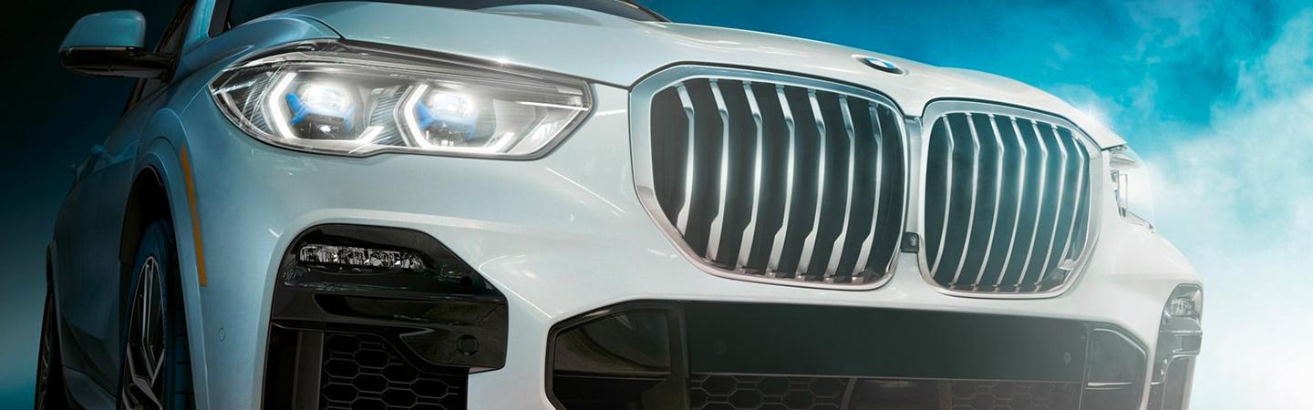 White 2021 BMW X5 parked front view angle with lights on