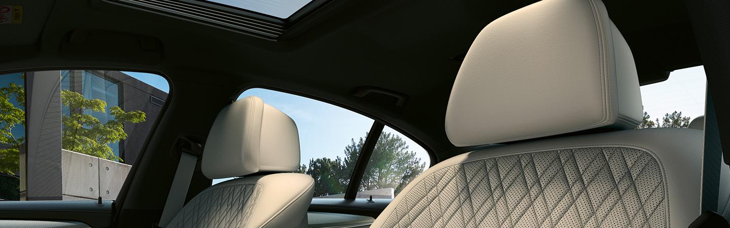 Interior view of the white leather headrests of the front seats in a BMW 5 Series.