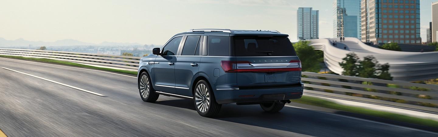 Rear side view of a blue 2020 Lincoln Navigator driving