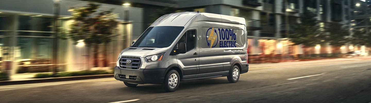 Side profile of a gray Ford E-Transit in motion