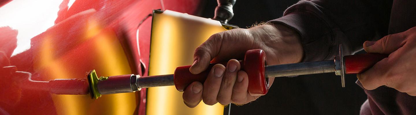 Close up view of a mechanic fixing a dent