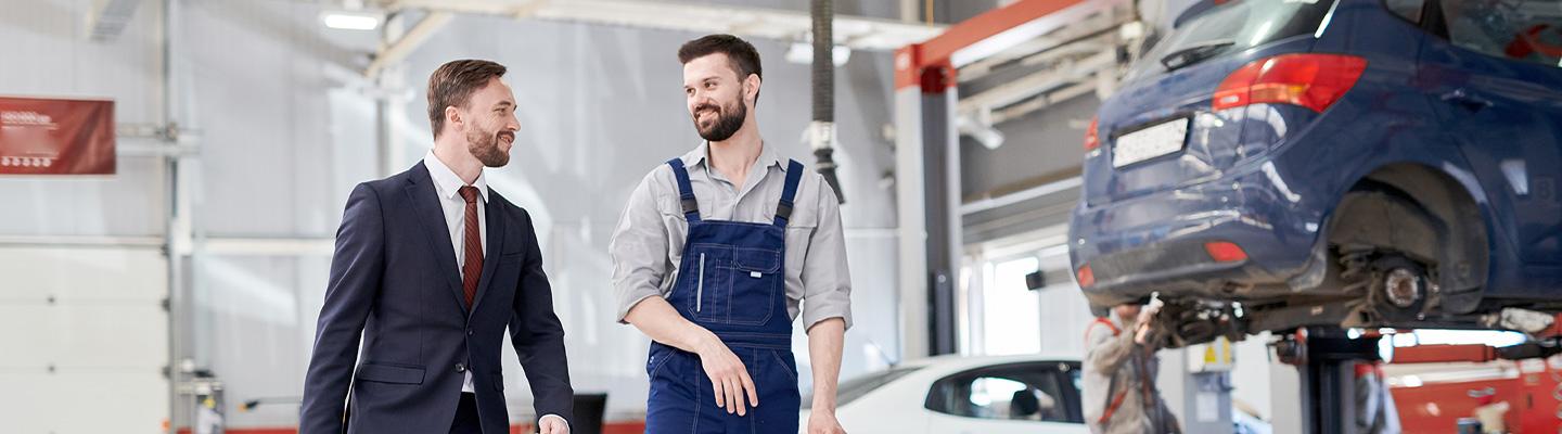 Two men discussing car repair in shop