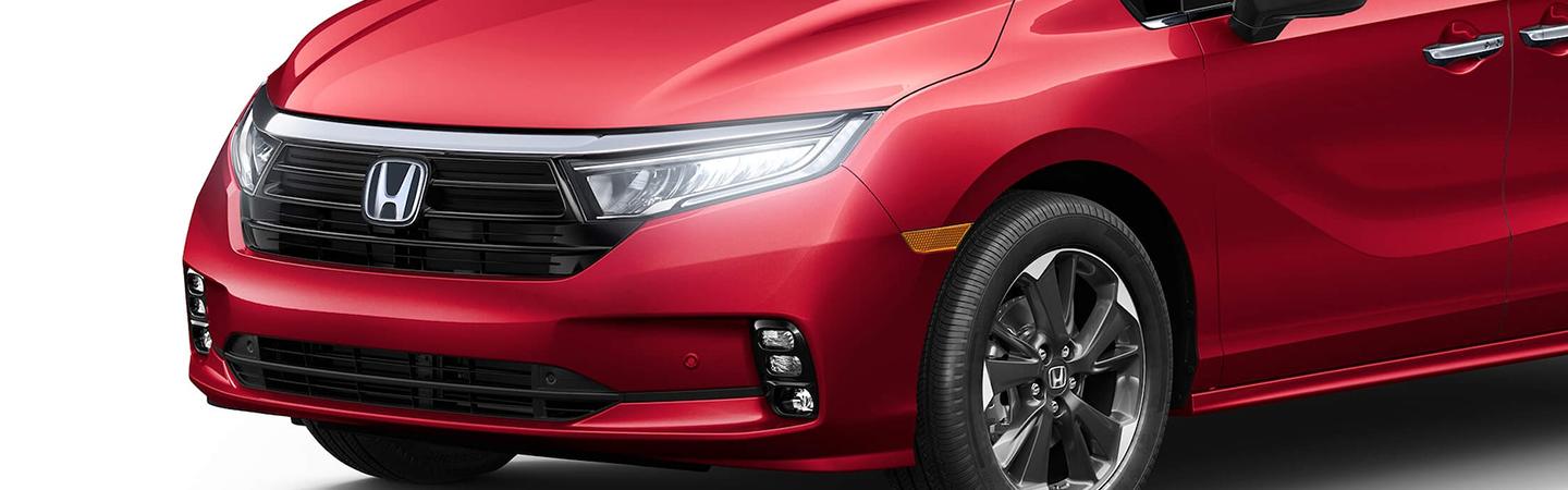 Close-up view of the headlights and front end of a red Honda Odyssey.