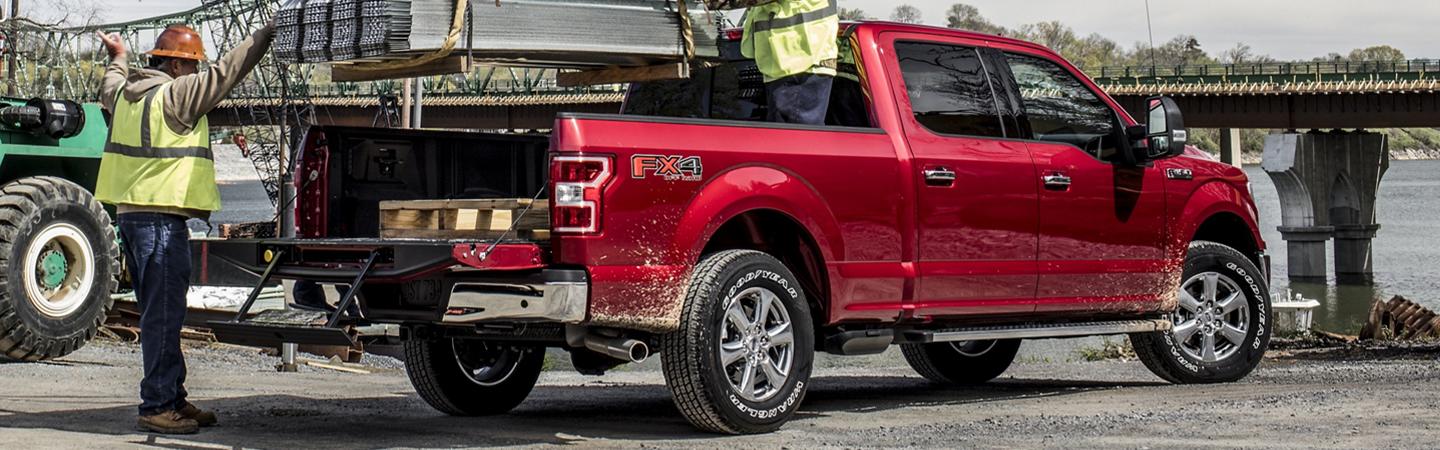 2020 Ford F-150 parked taking a load in back from crane with two workers