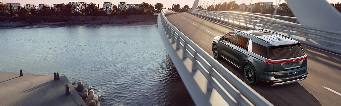 Top view of a silver Kia Carnival driving over a bridge.