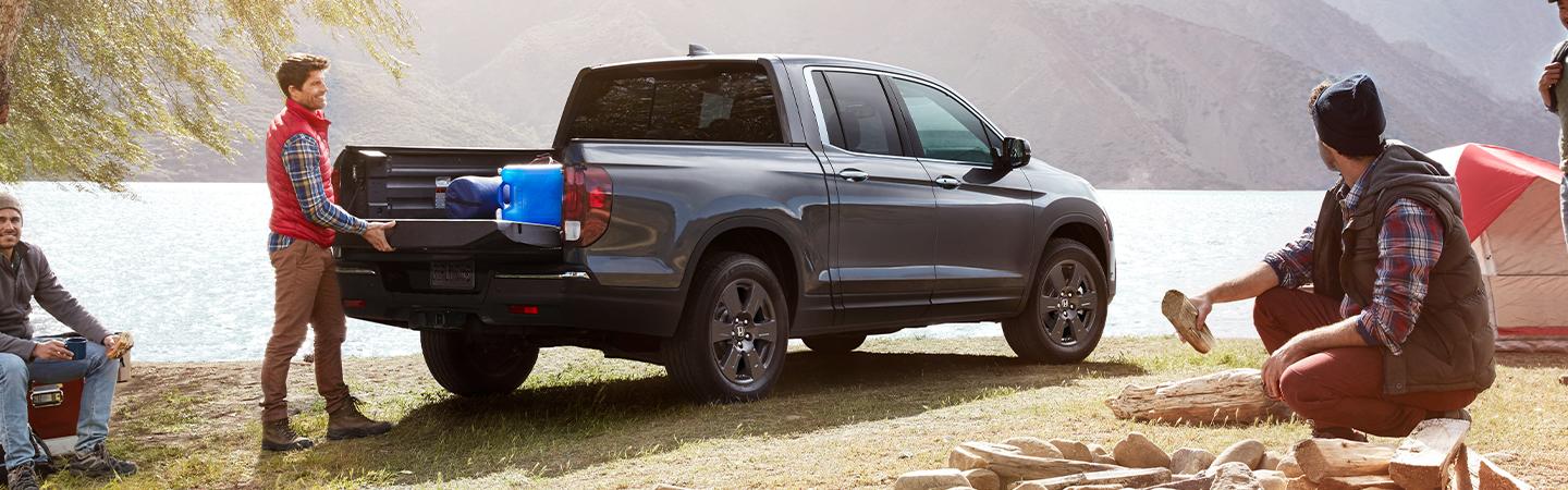 Man unloading cargo from the 2020 Honda Ridgeline parked near a lake
