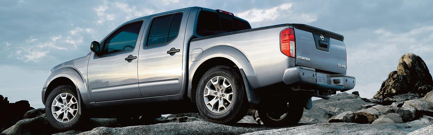 Silver Nissan Frontier parked on a boulder.