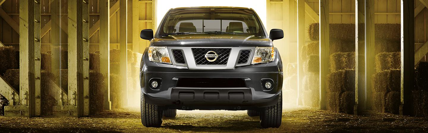 Front view of a grey Nissan Frontier in a hay barn.