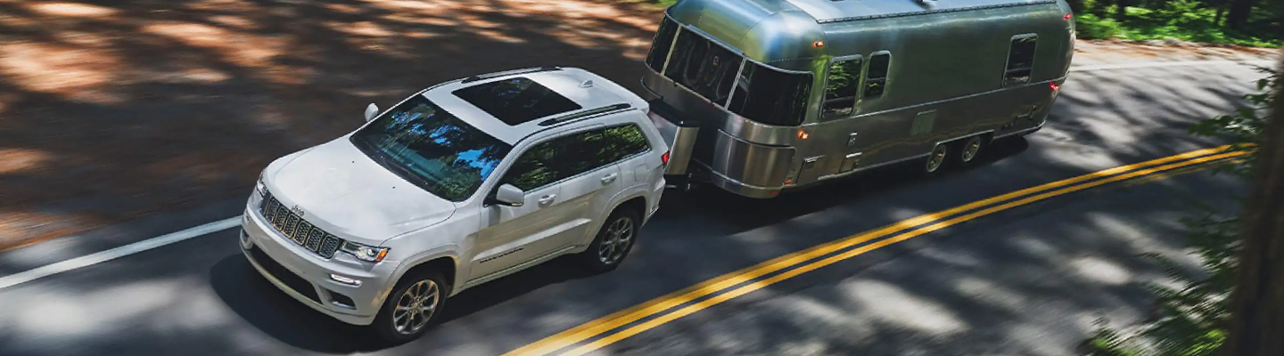 White Jeep towing camper