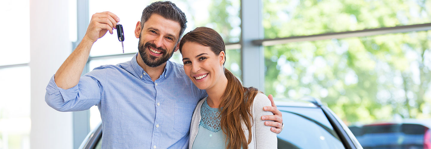 Man and woman smiling and holding a car key