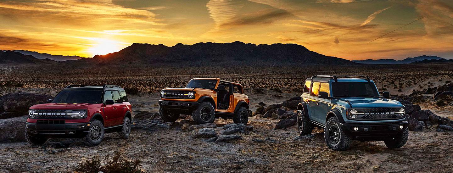 Three Ford Broncos parked outside on rugged terrain