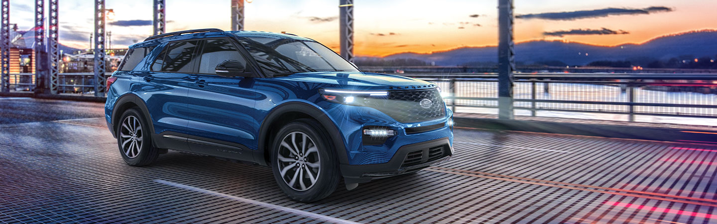 Angled profile of a blue Ford Explorer driving over a bridge