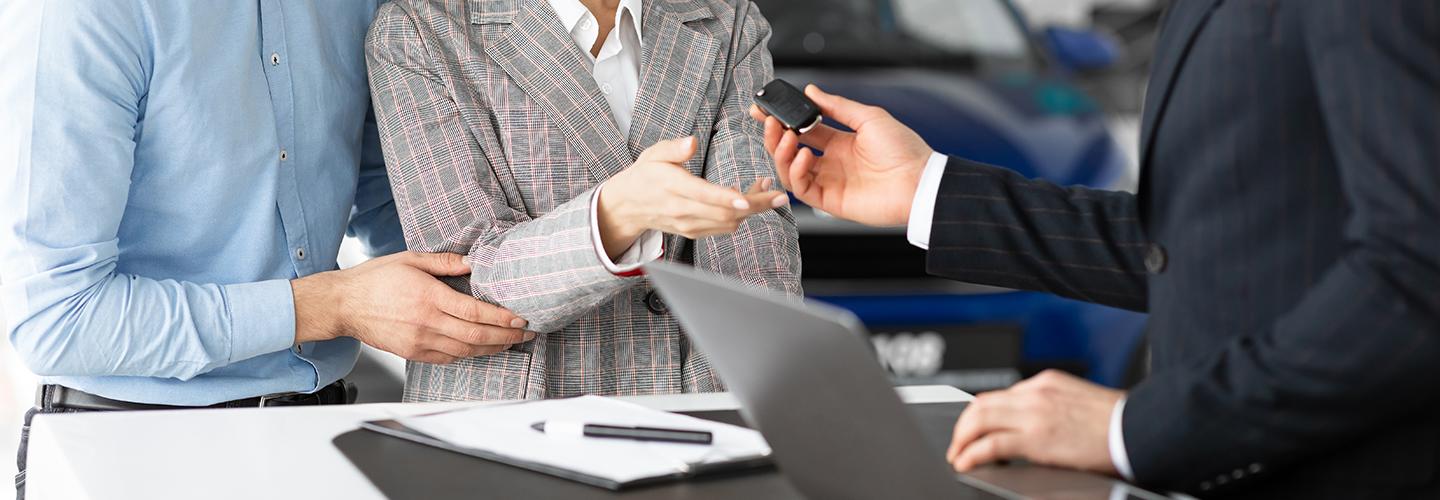 couple receiving keys in car showroom