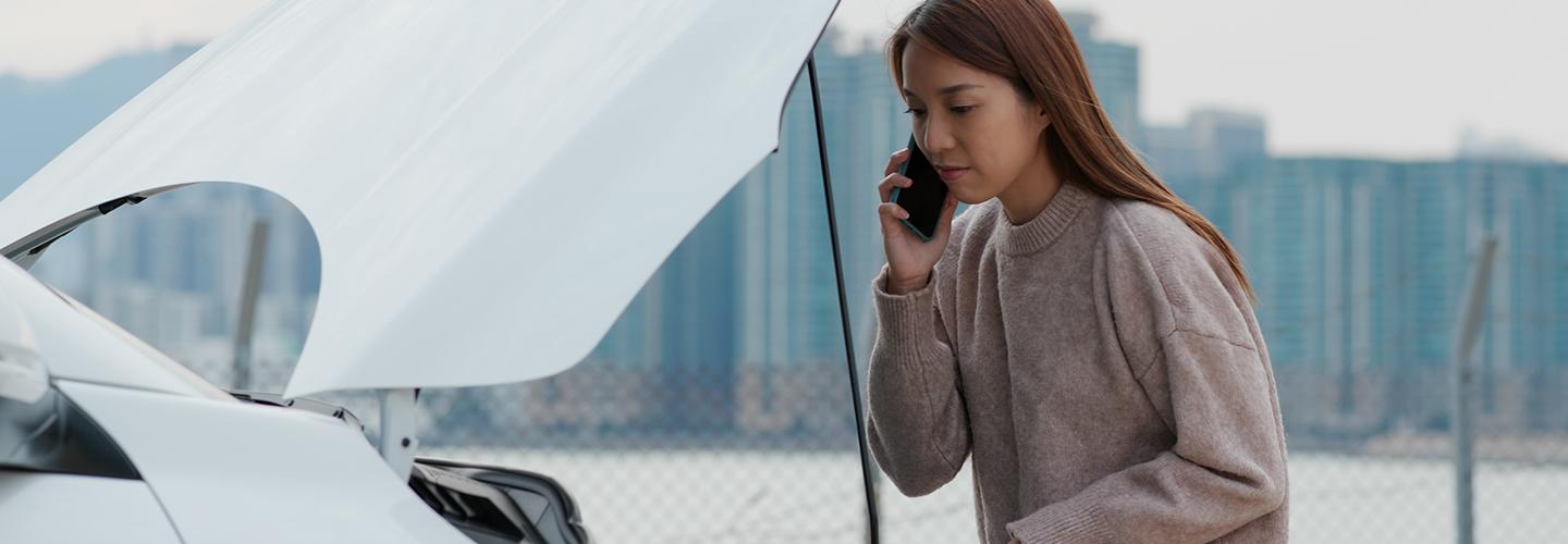 woman on phone with hood of car open