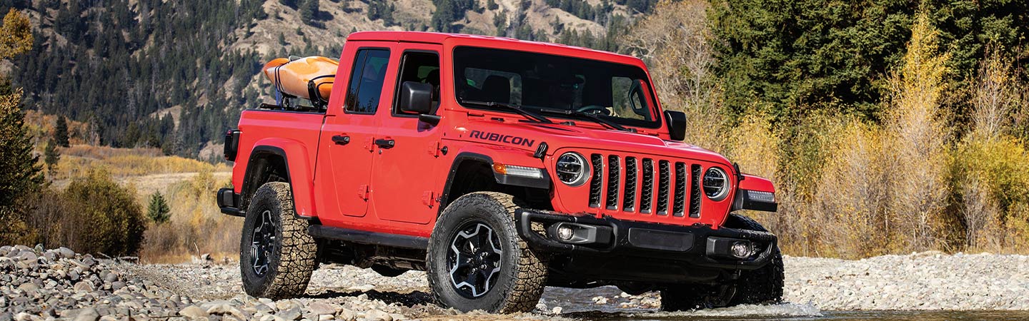 Red Jeep Gladiator crossing a creek