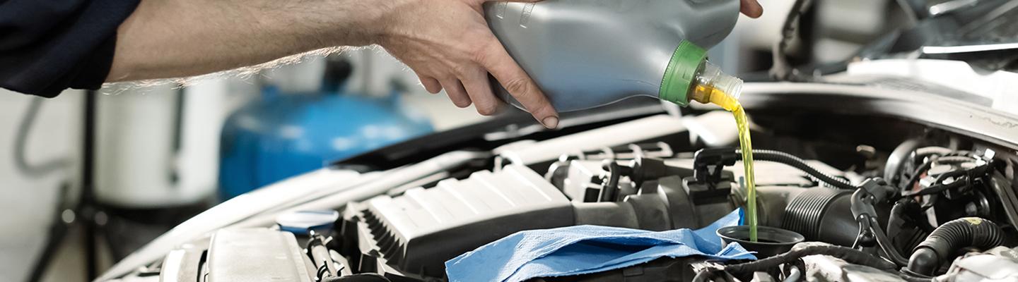 Auto mechanic pouring oil into engine