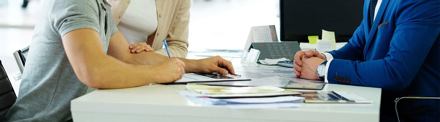 Customers signing documents inside of a car dealership