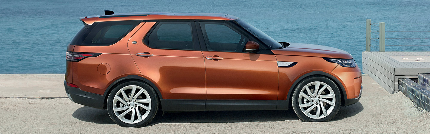 Drivers side profile of orange Land Rover Discovery
