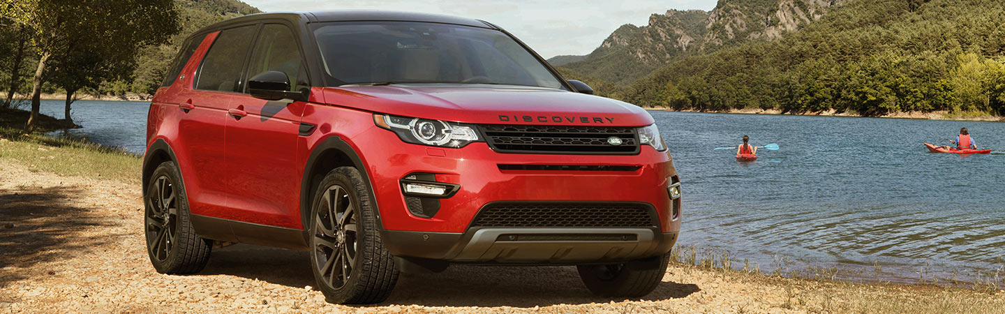 Red Land Rover Discovery Sport parked by a lake