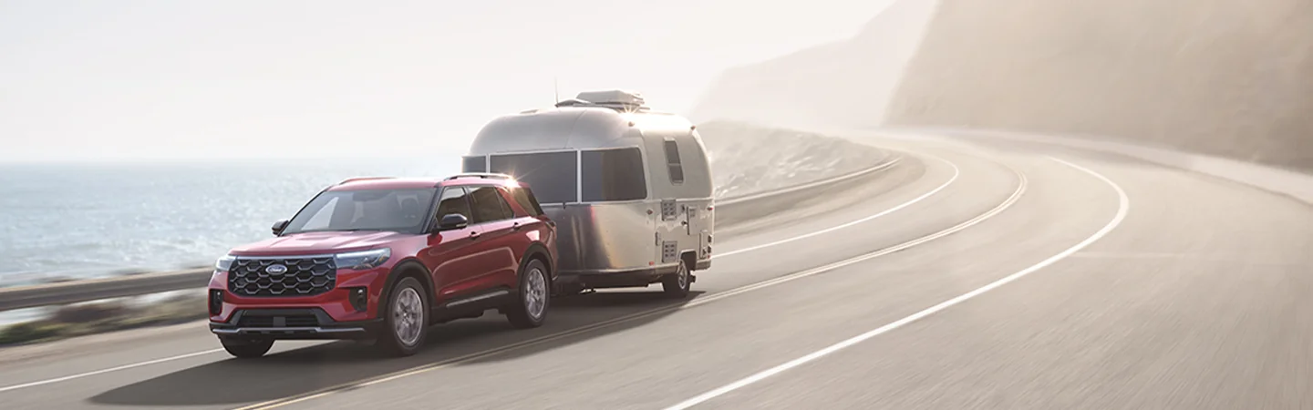 2025 Ford Explorer ST towing a camper on a scenic seashore road
