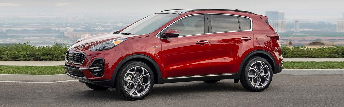 Left side profile of a red Kia Sportage parked